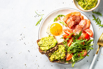 Beacon, eggs, toast with avocado and fresh salad. Healthy food, paleo diet. Top view on white kitchen table.