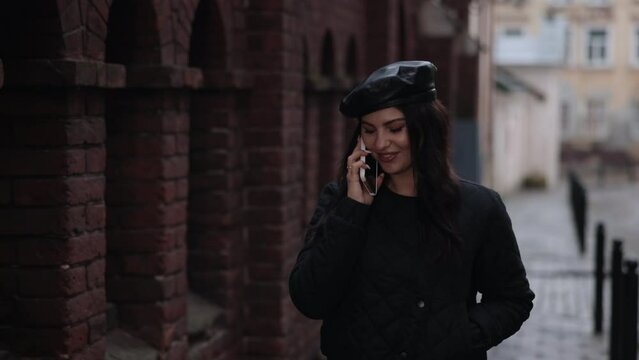 talkative pedestrian, pavement discussion, mobile talk. Young lady strolls along sidewalk, engaged in phone conversation.