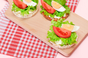 Rice Cake Sandwiches with Tomato, Lettuce and Egg on Wooden Cutting Board. Easy Breakfast. Diet Food. Quick and Healthy Sandwiches. Crispbread with Tasty Filling. Healthy Dietary Snack
