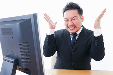 パソコンの前で憤慨するビジネスマン