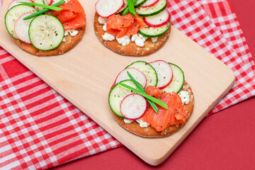 Fototapeta na wymiar Crispy Cracker Sandwiches with Fresh Salmon, Cucumber, Radish, Cottage Cheese and Green Onions. Easy Breakfast. Quick and Healthy Sandwiches. Crispbread with Tasty Filling. Healthy Dietary Snack