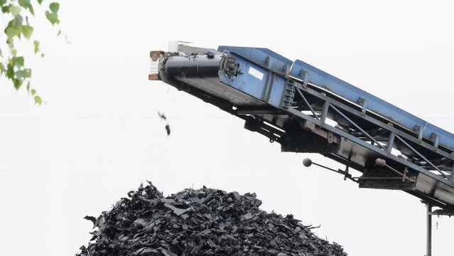 recycling and processing of old tires, crushed rubber go on a conveyor belt to a container