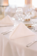 A folded napkin in a fancy triangle at a dinner reception with flatware and water glasses on the table.