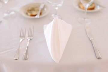 White napkin folded into a triangle with flatware at a formal dinner at a wedding reception