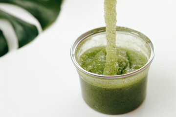 Green Natural Organic Polish Exfoliator Scrub Flows into a Jar on White background