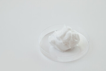 White Cosmetics Foam in Glass Lab Petri Dish on White background