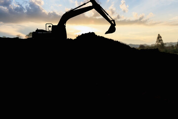 Crawler excavators silhouette are digging the soil in the construction site. on the cloud sky background with sunset