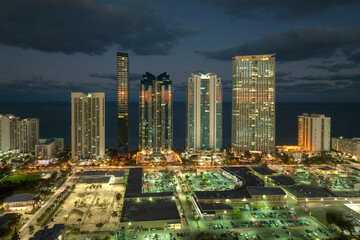 Fototapeta na wymiar View from above of brightly illuminated high skyscraper buildings in downtown district of Sunny Isles Beach city in Florida, USA. American tourist urban district at night