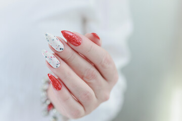 Female hands with long nails and bright red and white manicure