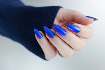 Woman's beautiful hand with long nails and bright blue manicure