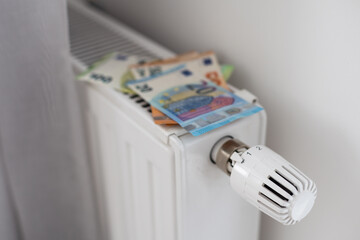 New thermostat with Euro cash on a radiator heating at home. Expensive heating costs symbolic image.