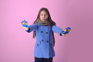 criança menina feliz cômica com roupas de frio da moda de inverno em fundo rosa 