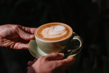 Beautiful serving of cappuccino in a mug on a dark background. The barista made coffee with beautiful foam