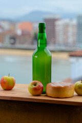 Traditional natural Asturian cider made from fermented apples in wooden barrels should be poured from great height for air bubbles into the drink and view on San Lorenzo beach of Gijon