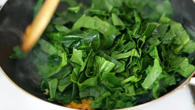 cooking spinach carrot and onion  in frying pan close up