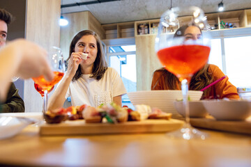 People eating at the table with the focus on the glass of wine