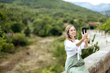 Close-up portrait of a young woman who takes a selfie against the backdrop of beautiful nature, a concept of tourism, copy space