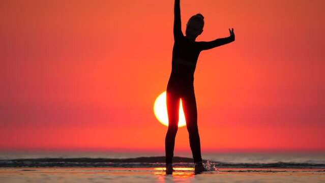 Sporty Girl Showcases Her Gymnastic Skills With Cartwheel At Serene Sea Shore. With Impressive Agility, She Confidently Stands On Her Hands, Extending Her Legs Overhead In Split. Silhouetted Shot.