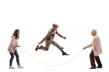 Elderly and young woman holding a rope and senior man skipping