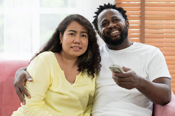 Happy young Asian woman and African American male spending time together at home
