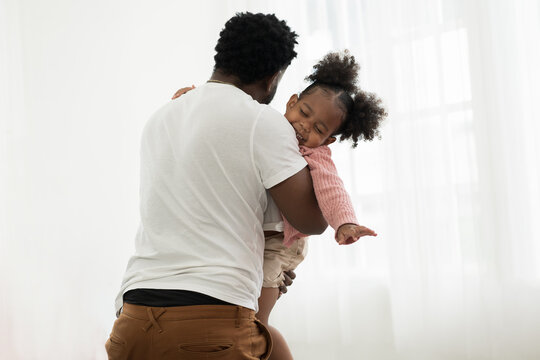 Happy father embracing his daughter. Father and daughter playing together at home. Happy African American little girl kid playing with dad. Happy African American family spending time together