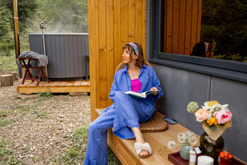 Woman resting on beautiful terrace of a wooden cottage on nature. Escaping to nature, calm and...