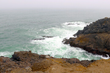 Fototapeta na wymiar The waves of the Pacific Ocean crash on the rocky coast.