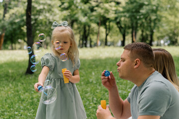 Obraz premium happy family relaxing outdoors in the park dad and daughter blowing soap bubbles Fun and carefree childhood family weekend father's day