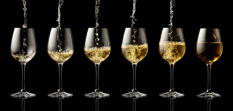 Pouring white wine into a glass on a black background.