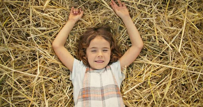 Children's dreams, the girl falls on the hay. The imagined cast lies on the field and looks at the sky. Happy carefree childhood. High quality 4k footage