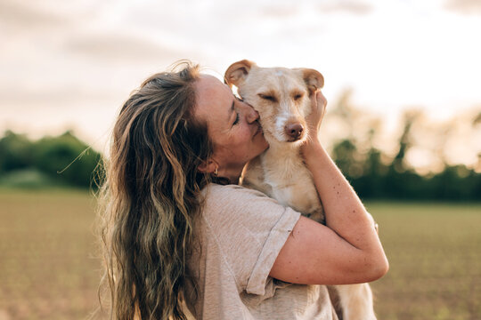 close up portrait of a happy woman hugging and kissing her dog