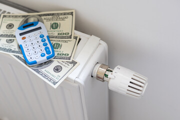 Calculator, banknotes lie on the radiator of the heating system, the cost of heat, utilities