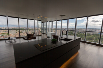 dark minimalistic design of a trendy chic studio apartment with panoramic windows on a high floor overlooking the city