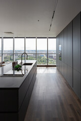 dark minimalistic design of a trendy chic studio apartment with panoramic windows on a high floor overlooking the city