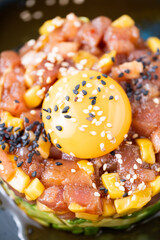 A detail of egg in a steak tartar with sesame seeds