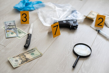 High contrast image of a crime scene with gun and markers on the floor