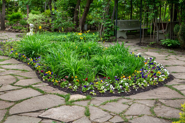 Fragment of a landscape park with flowerbeds and paths, paved stones