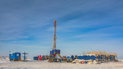 Fototapeta na wymiar Well repair at a gas field in the Arctic. Winter polar day. Frost. Snow. Mobile rig for well repair with a derrick and other equipment. A helicopter is flying in the background