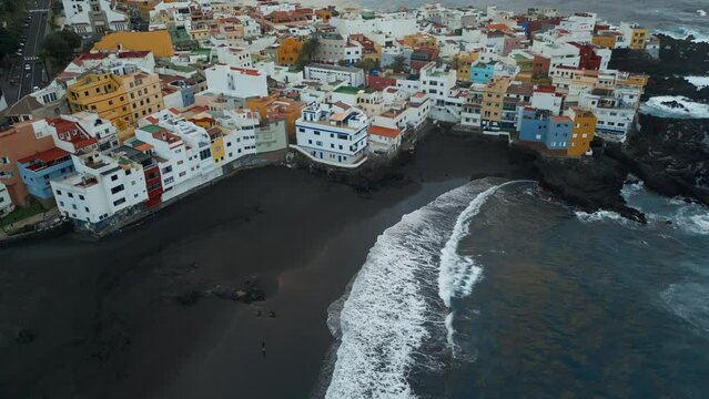 black volcanic sand beach and cozy village on shore of Atlantic Ocean with blue water, Punta Brava, Tenerife