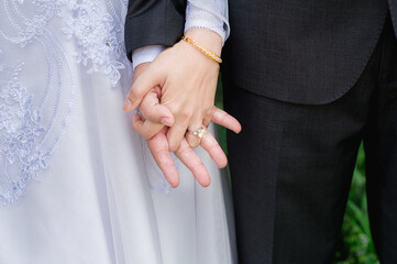 woman bride wears a wedding ring on the left ring finger of the groom's hand on black background.concept for wedding card background, poster,Invitation card