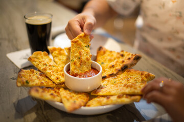 Close up breadsticks dipped in marinara