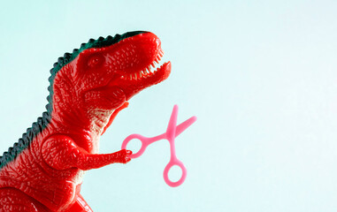 Close up red dinosaur holding tiny scissors. Beauty care, hairdressing concept.