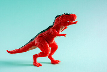 Red dinosaur toy on blue background.