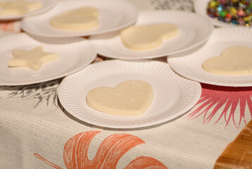Cut out figures from dough in disposable cardboard plates. The process of making cookies or shortbread.