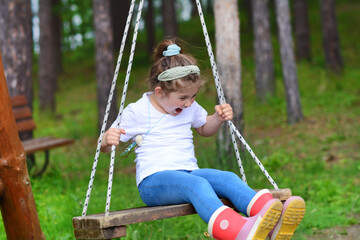 Child laughing on a  swing. Toddler girl on a playground 