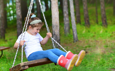 Child laughing on a  swing. Toddler girl on a playground 