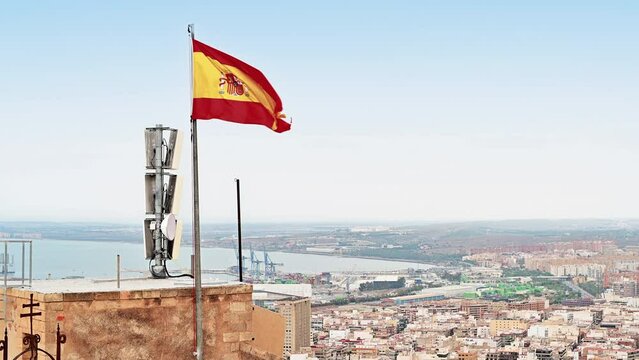 Spanish flag waving on top of the town Alicante in Spain