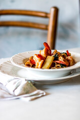 Close up of a plate with spinach pasta with grilled shrimps on served table