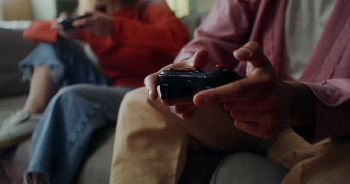 Two people are playing video games at home. Close-up of male hands with a joystick, no face