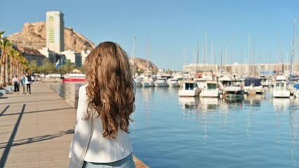 Woman walking on a dock near Port of Alicante. Mountain and boats in the background
